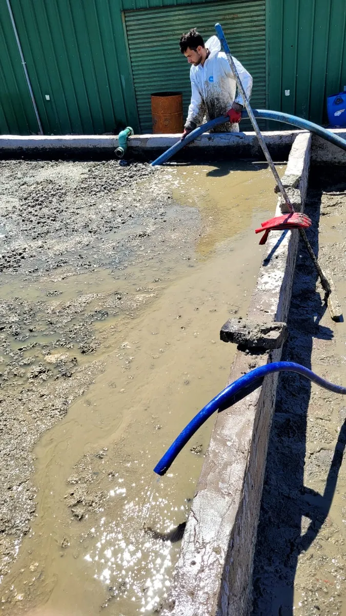 Operario de Mi País succionando líquidos de una canaleta